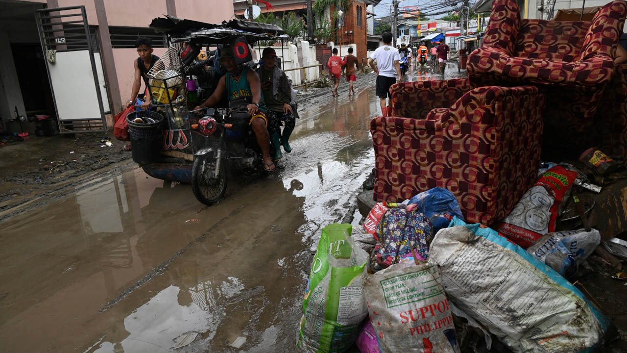 Philippine rescuers on Monday waded through thigh-deep mud using long pieces of wood to search for bodies buried by a landslide, as the death toll from a powerful storm rose to 98. Just over half of the fatalities were from a series of flash floods and landslides unleashed by Tropical Storm Nalgae, which destroyed villages on the southern island of Mindanao on Friday. Mindanao is rarely hit by the 20 or so typhoons that strike the Philippines each year, but storms that do reach the region tend to be deadlier than in Luzon and the central parts of the country. There is little hope of finding survivors in the worst-hit areas after the storm swept across the archipelago nation, inundating communities in and around the capital Manila over the weekend. The national disaster agency has recorded 63 people still missing and scores of others injured. Perfidia Seguendia, 71, and her family lost all their belongings except the clothes they were wearing when they fled to their neighbour’s two-storey house in Noveleta municipality, south of Manila. “Everything was flooded — our fridge, washing machine, motorcycle, TV, everything,” Seguendia told AFP. “All we managed to do was to cry because we can’t really do anything about it. We weren’t able to save anything, just our lives.” The Philippine Coast Guard posted pictures on Facebook showing its personnel in the devastated Kusiong village, in Maguindanao del Norte province of Mindanao, struggling through thick, thigh-deep mud and water as they searched for more bodies. Kusiong was buried by a massive landslide, which created a huge mound of debris, just below several picturesque mountain peaks. Rescuers poked long pieces of wood into the morass looking for five missing villagers, after recovering 20 bodies in recent days, the coast guard said. “We have shifted our operation from search and rescue to retrieval because the chances of survival after two days are almost nil,” said Naguib Sinarimbo, civil defence chief of the Bangsamoro region in Mindanao. Meanwhile, survivors faced the heartbreaking task of cleaning up their sodden homes. Residents shovelled mud from their houses and shops after piling their furniture and other belongings in the streets of Noveleta. “In my entire life living here, it’s the first time we experienced this kind of flooding,” said Joselito Ilano, 55, whose house was flooded by waist-high water. “I am used to flooding here but this is just the worst, I was caught by surprise.” – More rain on the way – President Ferdinand Marcos began touring some of the hard-hit areas on Monday, including Noveleta, as aid agencies rushed food packs, drinking water and other relief to victims. Marcos said preemptive evacuations in Noveleta had saved lives. “While the calamity was huge, the number of casualties was not that high, although there’s a lot of damage to infrastructure,” he said. Nalgae inundated villages destroyed crops and knocked out power in many regions as it swept across the country. It struck on an extended weekend for All Saints’ Day, which is on Tuesday when millions of Filipinos travel to visit the graves of loved ones. Scientists have warned that deadly and destructive storms are becoming more powerful as the world gets warmer because of climate change. The state weather forecaster warned that another tropical storm was heading towards the Philippines even as Nalgae moved across the South China Sea. Starting Wednesday, the new weather system could bring more heavy rain and misery to southern and central regions badly affected by Nalgae. Landslides and flash floods originating from largely deforested mountainsides have been among the deadliest hazards posed by storms in the Philippines in recent years.